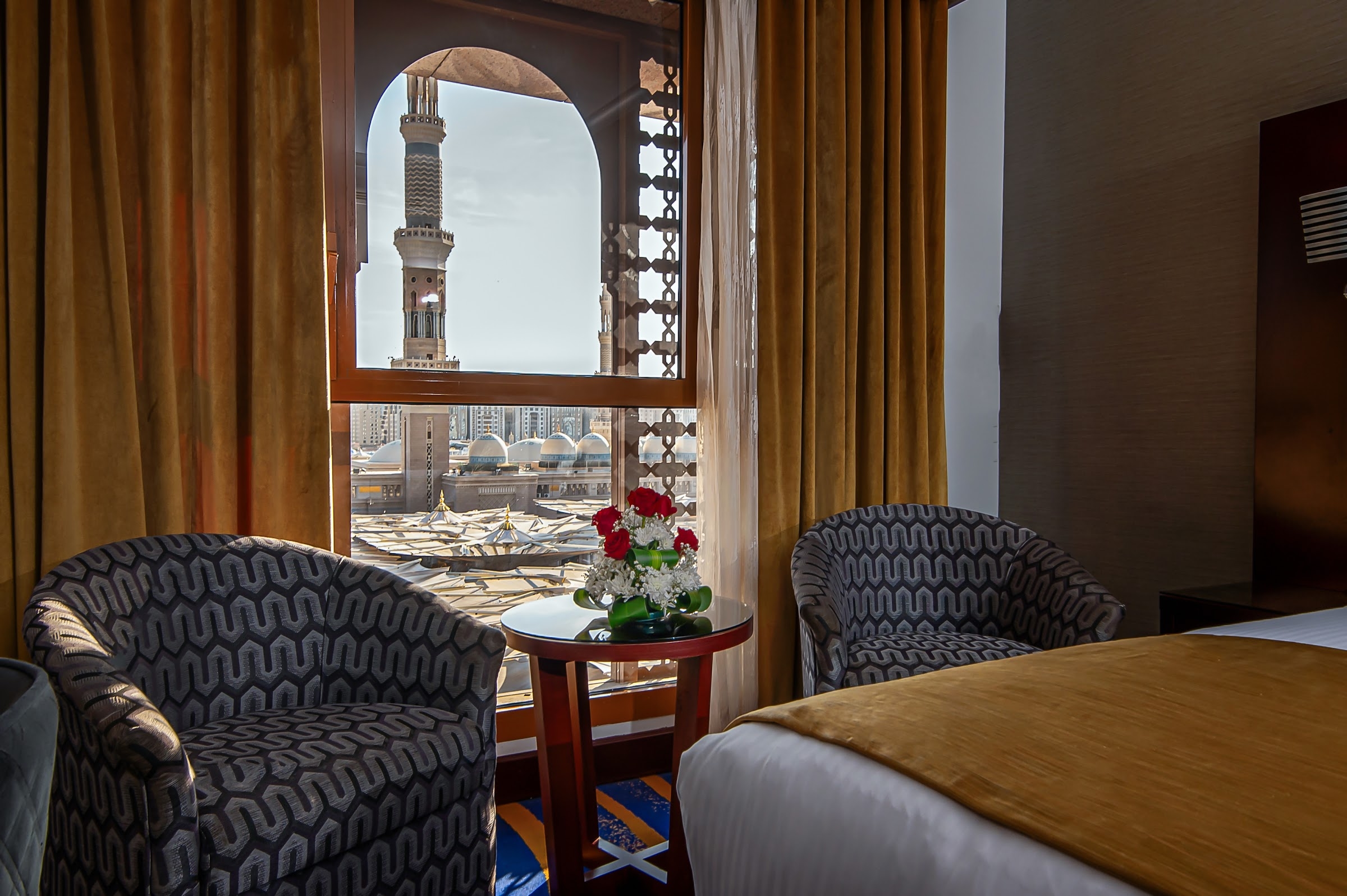 A room with a minaret and the domes of the Prophet's Mosque beyond the window
