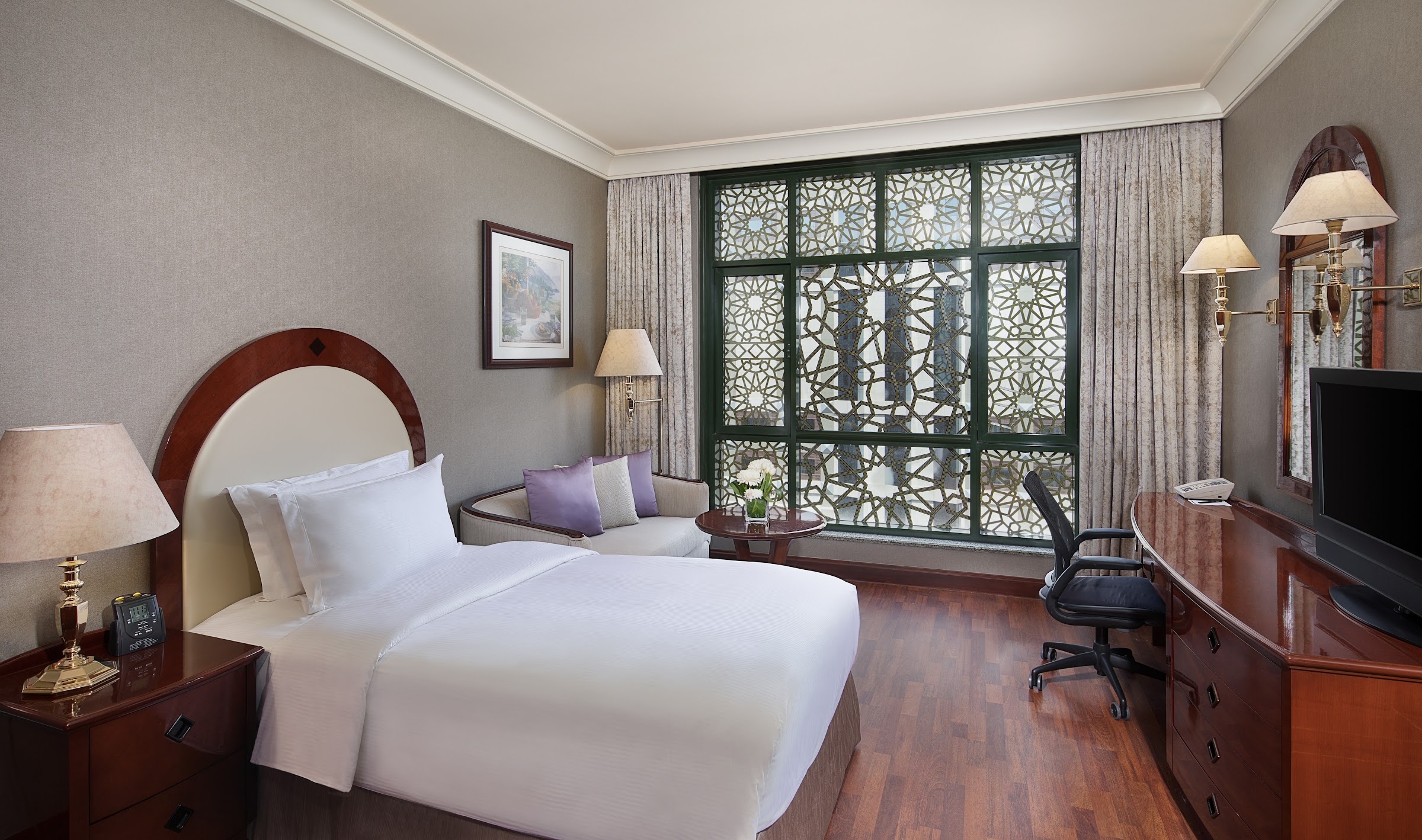 A room with a king bed and a lattice window