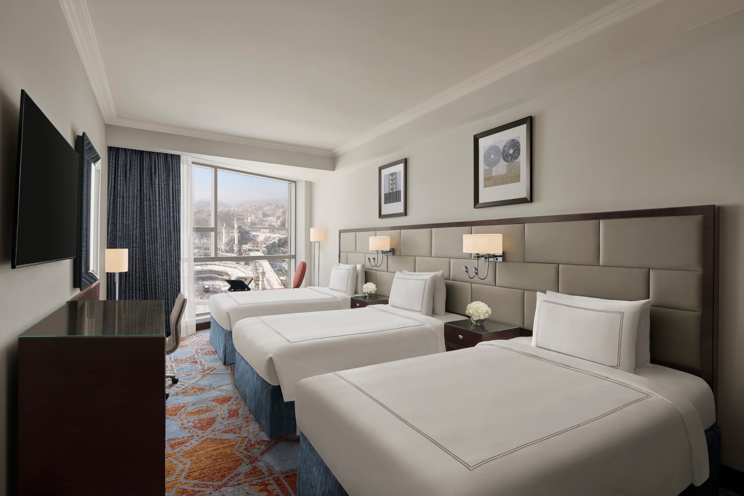 Une chambre avec trois lits simples, le Haram derrière la fenêtre